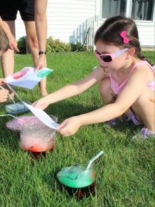 A girl presses a piece of paper onto colorful bubbles