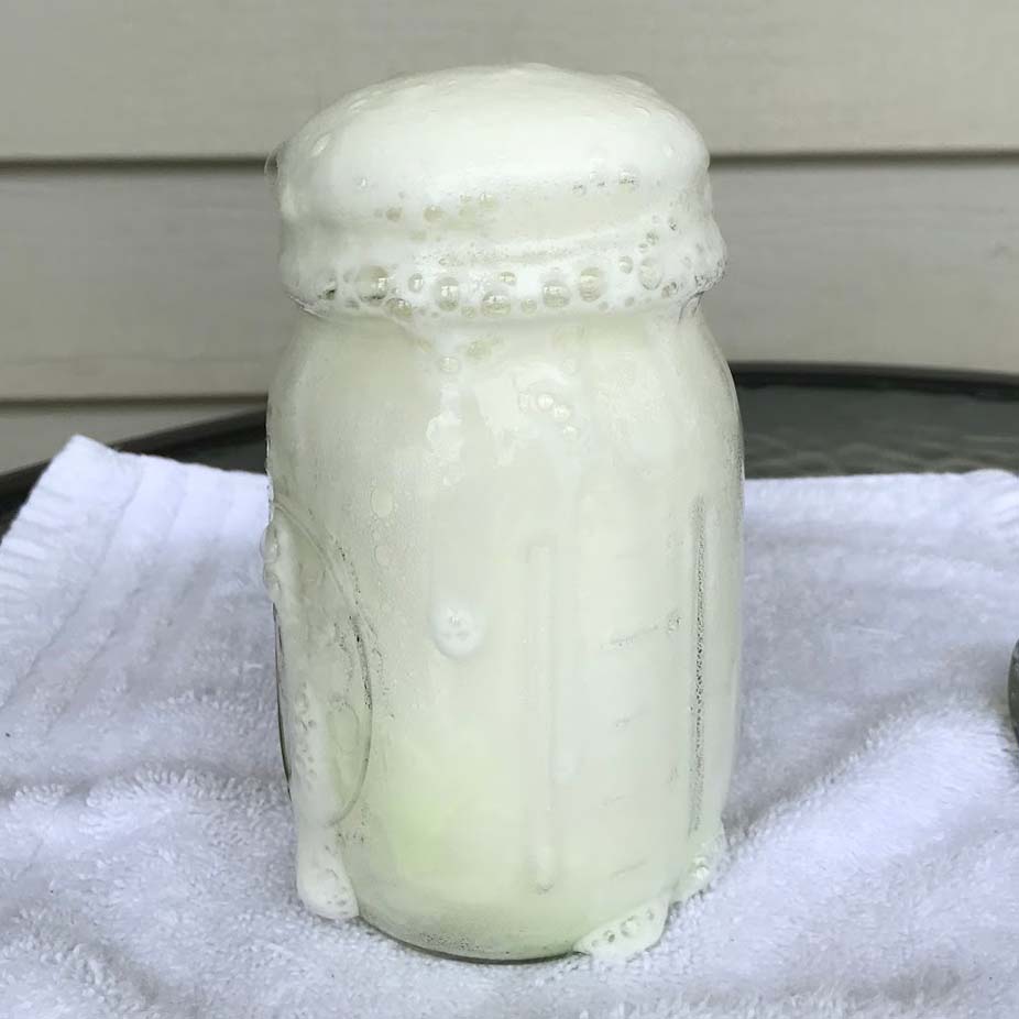 A mason jar filled with foam, some overflowing and dripping down the jar
