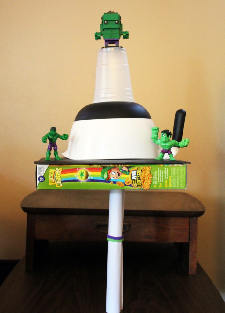 A tower with a cereal box, bowl and plastic Hulk figurines 