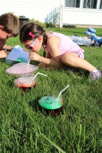 A girl blows colorful bubbles into a cup