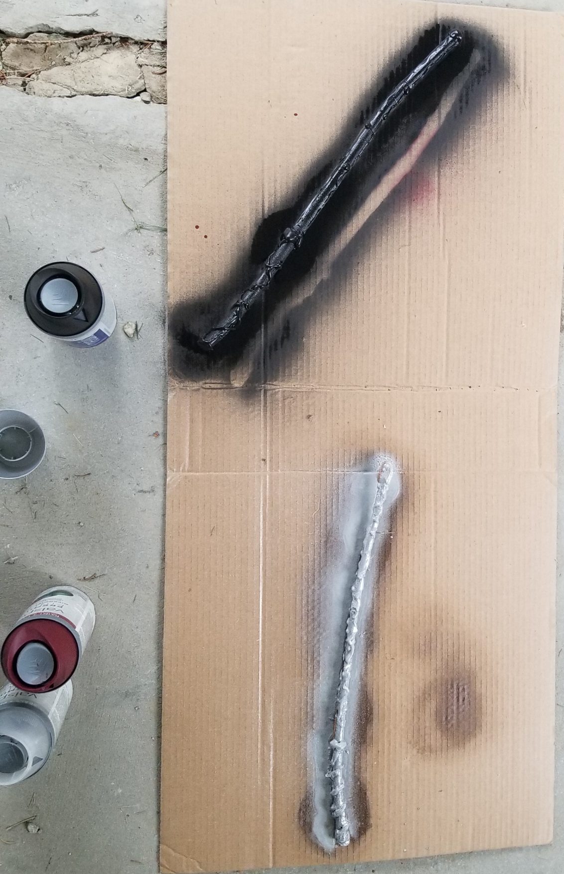 two sticks with hot glue painted and laying on a piece of cardboard