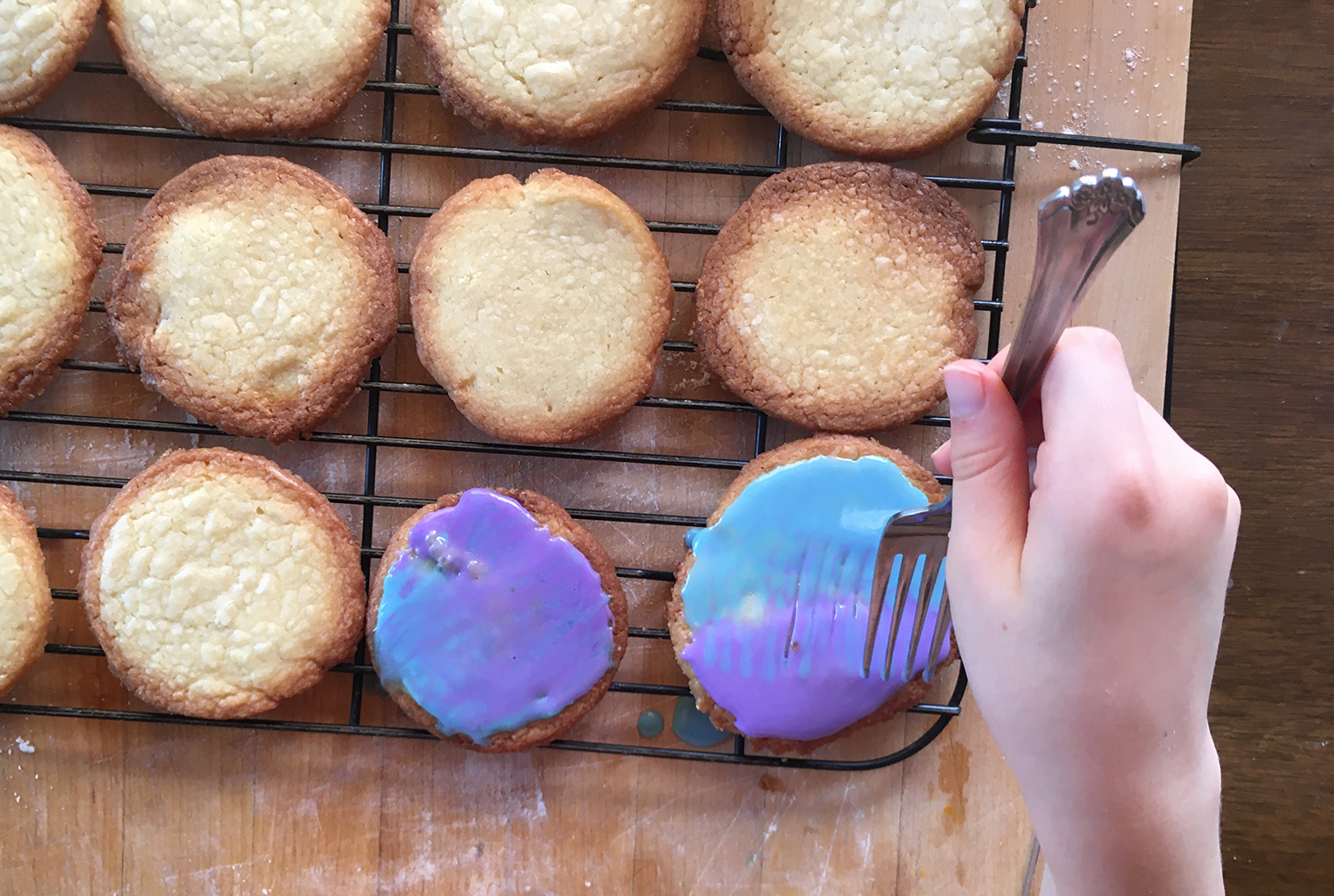 Cookies shown from above as someone uses a fork to swirl frosting