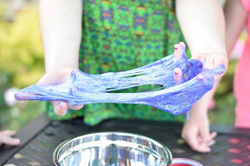 A child spreads purple slime between her hands