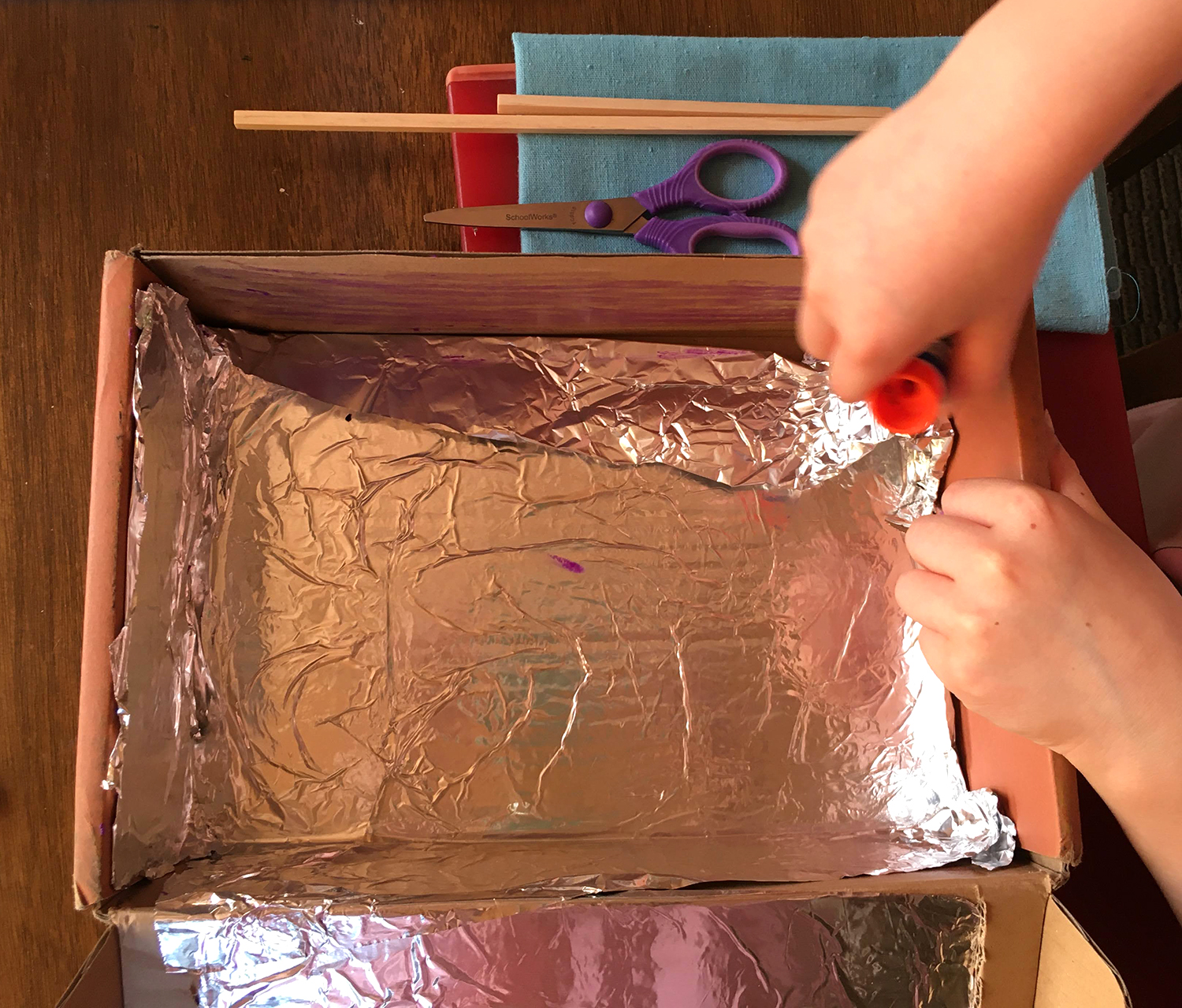 Child glues foil into a box